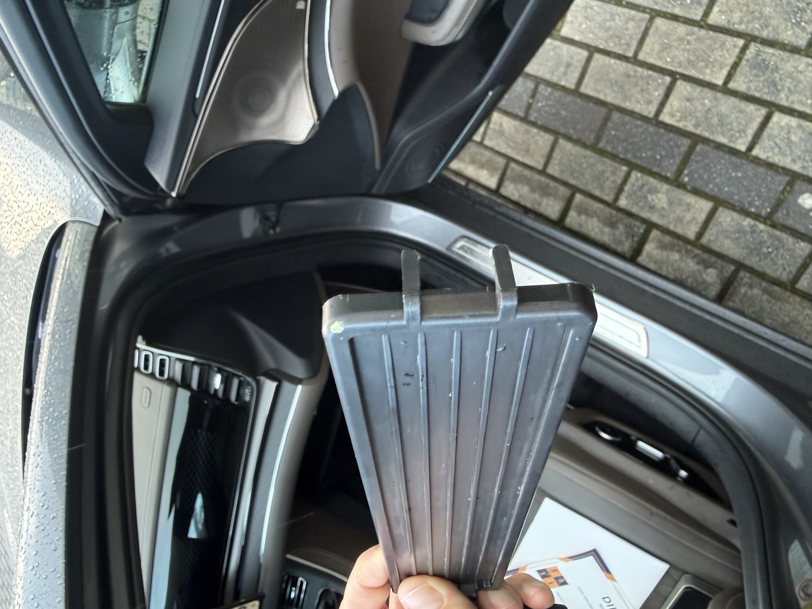 Broken plastic cover of the BYD Han cabin filter compartment, removed from behind the glovebox, with the snapped retaining latch visible