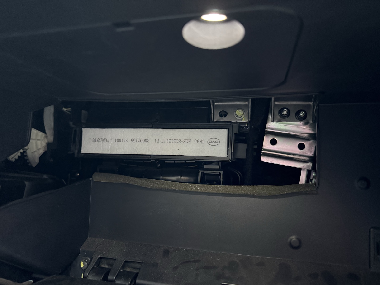 BYD Han CN95 cabin filter fitted upside down in the housing behind the glovebox, with the printed label and airflow arrows appearing inverted